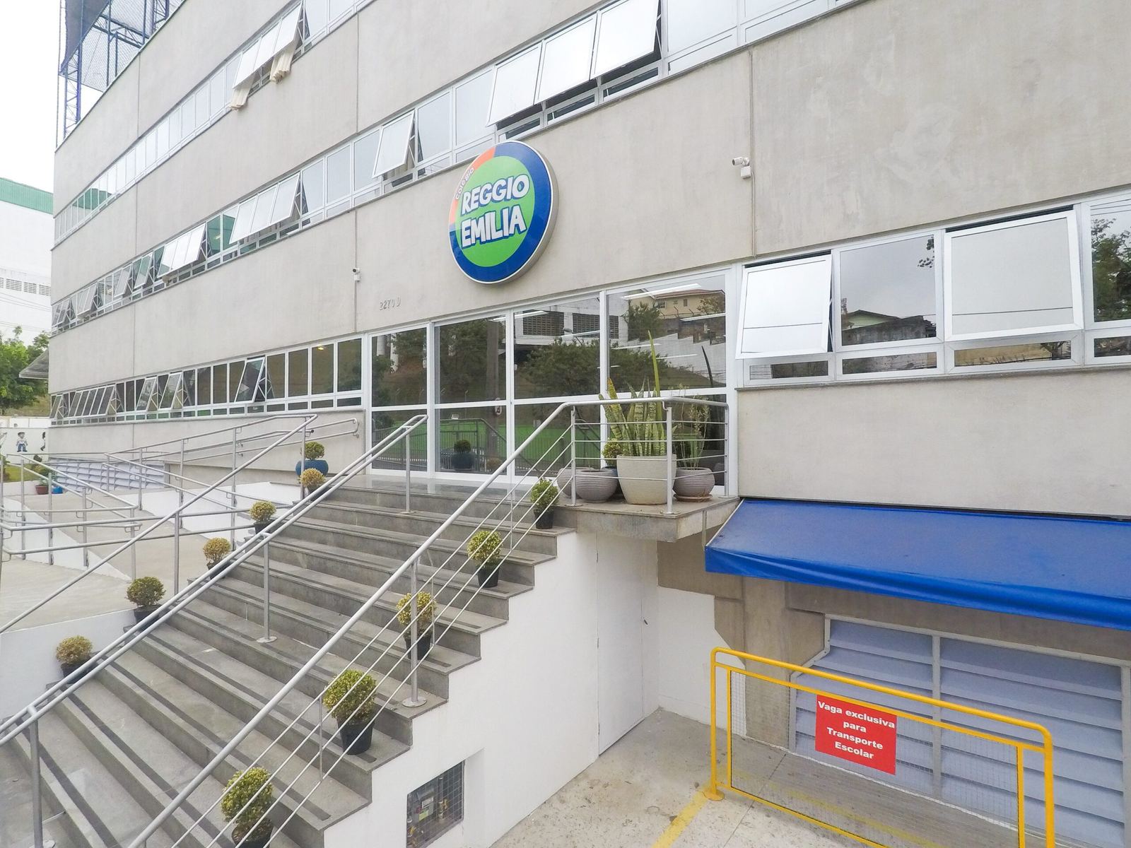 Fachada do prédio do Colégio Reggio Emilia, com o logo do colégio e a escadaria de entrada